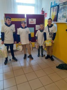 Wolontariusze z darami na tle tablicy informującej o wspieraniu Ukrainy