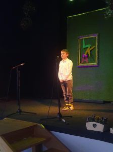 na zdjęciu uczennica recytuje wiersz na scenie