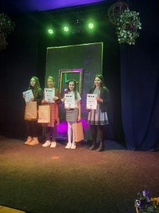 Na zdjęciu uczniowie  trzymają w dłoniach nagrody i nominacje do etapu powiatowego