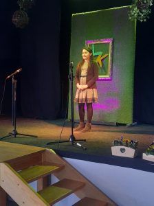 na zdjęciu uczennica recytuje wiersz na scenie