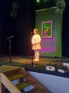 na zdjęciu uczennica recytuje wiersz na scenie