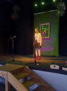 na zdjęciu uczennica recytuje wiersz na scenie