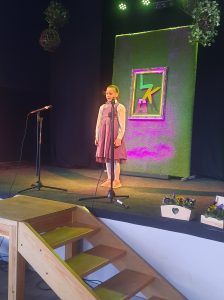 na zdjęciu uczennica recytuje wiersz na scenie