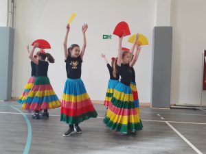 grupa dziewcząt w kolorowych spódnicach w tańcu