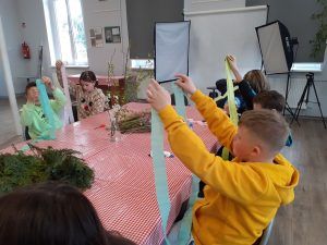 na zdjęciu uczniowie przygotowujący bibułę do tworzenia kwiatów