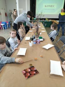 dzieci przy stołach ozdabiają jajka