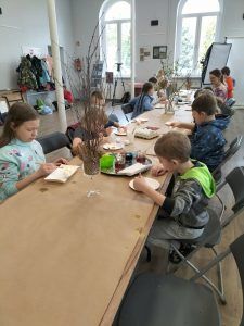 dzieci przy stołach ozdabiają jajka