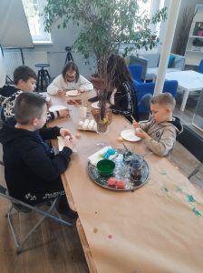 uczniowie przy stole zdobią jajka woskiem