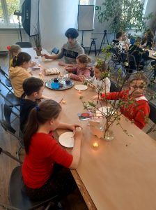 uczniowie przy stole zdobią jajka woskiem