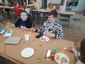 uczniowie przy stole zdobią jajka woskiem