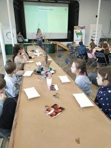 dzieci przy stołach ozdabiają jajka