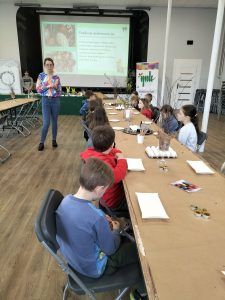 dzieci przy stołach ozdabiają jajka