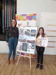 na zdjęciu dyrektor ośrodka kultury i uczennica przy wystawie fotograficznej