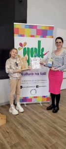 na zdjęciu uczennica i dyrektor ośrodka kultury z pracą konkursową - zającem z drewna