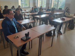 na zdjęciu uczniowie zadający pytania gościowi