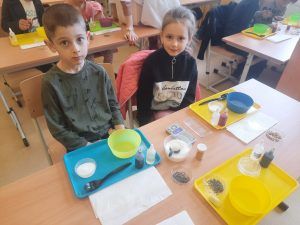 uczniowie przy stolikach odmierzają składniki 