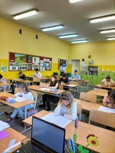 Uczniowie siedzący w ławkach podczas egzaminu trzecioklasisty