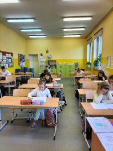 Uczniowie siedzący w ławkach podczas egzaminu trzecioklasisty