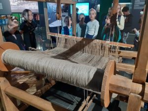 uczniowie przy krośnie tkackim
