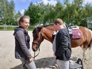 uczeń przy opiekunie głaszcze konia