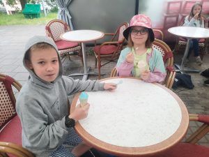 Uczniowie klasy trzeciej zajadają lody przy stoliku