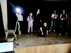 Fotografia grupowa uczestniczek warsztatów fotograficznych i fotografika prowadzącego zajęcia.