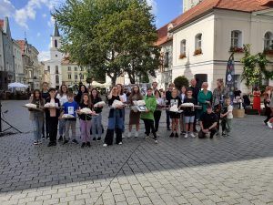 Grupową fotografia finalistów konkursu z otrzymanymi nagrodami. Młodzież stoi przed ratuszem.