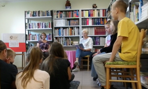 grupa uczniów słucha czytanego utworu przez zaproszonego gościa