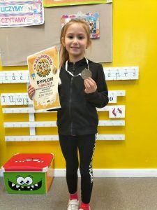 Uczennica prezentuje dyplom oraz medal