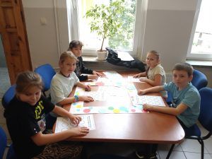 grupa uczniów przy stoliku z zadaniami