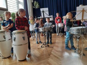Dzieci stoją przy instrumentach perkusyjnych.