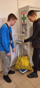 dwaj uczniowie ważą zebrane baterie i nakrętki