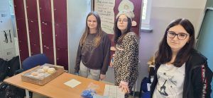 trzy uczennice przy stoisku z pączkami