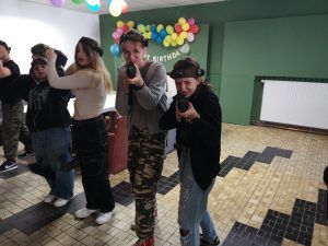 grupa uczennic na strzelnicy celująca w obiektyw aparatu