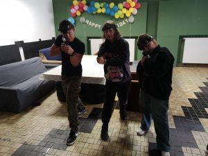 grupa uczniów na strzelnicy celująca w obiektyw aparatu