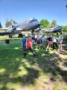 grupa uczniów przed muzealnymi samolotami