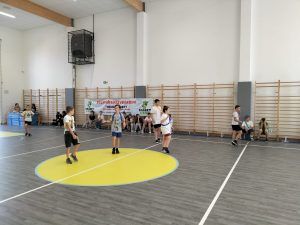 Uczniowie grający w piłkę na sali gimnastycznej. 