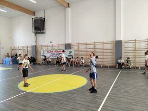 Uczniowie grający w piłkę na sali gimnastycznej. 