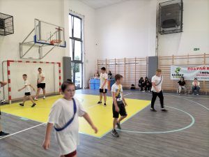 Uczniowie grający w piłkę na sali gimnastycznej. 