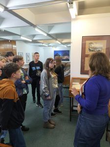 uczniowie w muzeum słuchają opowieści o historii książki i ilustracji