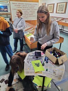 Uczniowie uczestniczą w warsztatach graficznych z wykorzystaniem prasy introligatorskiej do złoceń