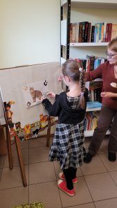 uczennica przed sztalugą z pracą prezentującą kota