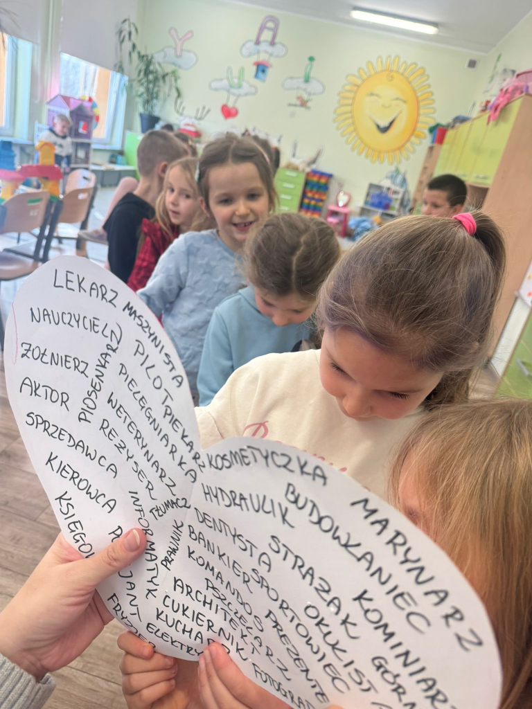 Dzieci przebijają szpilką kartkę z sercem i imionami jako wróżbę miłosną.