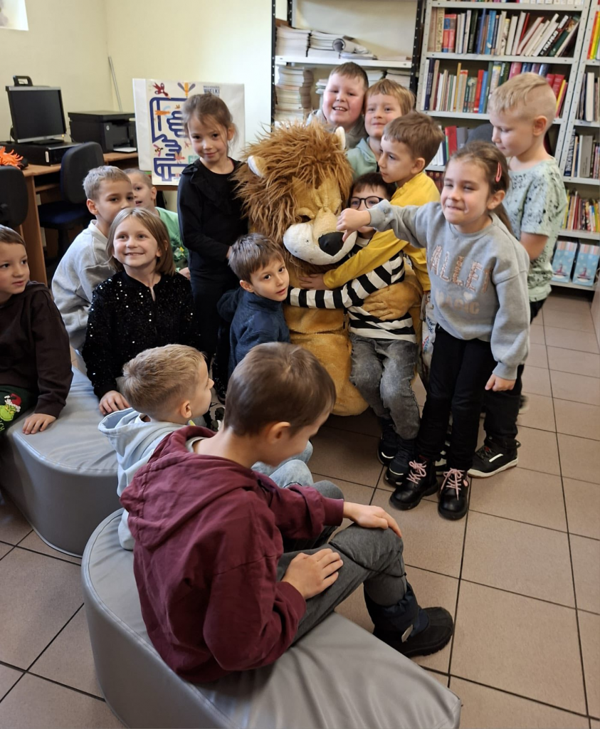 Uśmiechnięta grupa dzieci przytula maskotkę lwa.