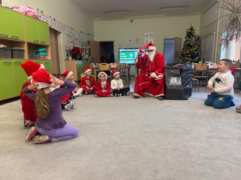 Dzieci siedzące w kole wraz ze Świętym Mikołajem.