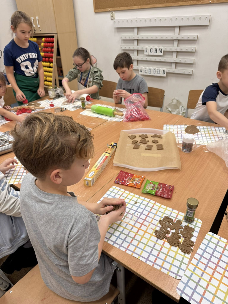 Grupa dzieci wycina z ciasta różnorodne kształty pierników.